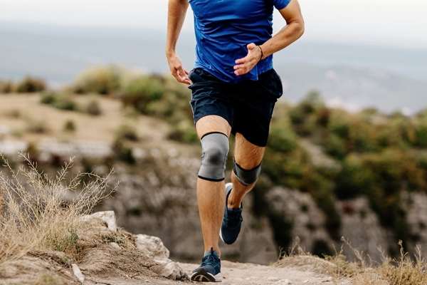 Man running with knee braces on a track